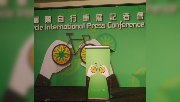Das Fahrrad in beiden Händen nach oben: Logo der Taipeh Show