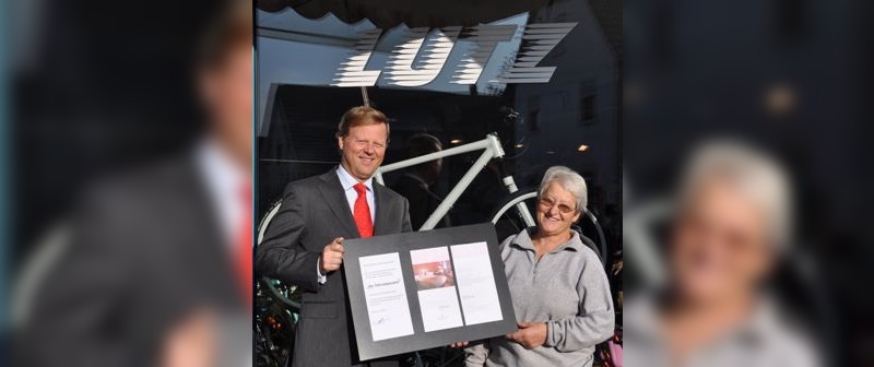 Ad Roest übergibt den Gutschein an die Gewinnerin Frau Lutz