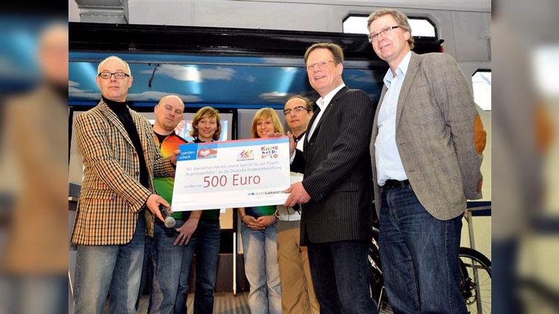 Im Bild von links: Jens Kort (Geschäftsführer Kinderkrebsstiftung), 3 RegenbogenfahrerInnen, Wigald Boning (Ehrenmitglied RadClub Deutschland), Georg Düsener (Vertriebsleiter Wertgarantie), Ulrich Fillies (Leitung RadClub Deutschland)