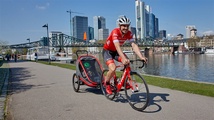 John Degenkolb radelt mit dem Hamax-Anhänger am Frankfurter Mainufer entlang.